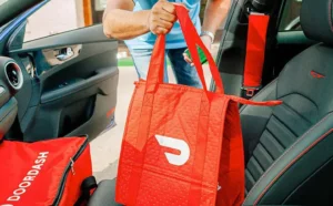 A Man Exiting a Car Holding DoorDash Bag